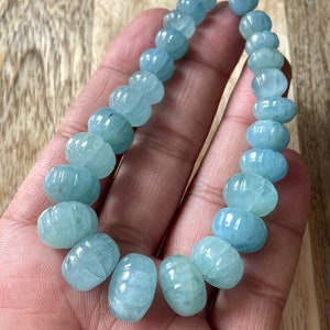 May include: A strand of light blue aquamarine beads, each bead is faceted and has a rounded, slightly elongated shape.