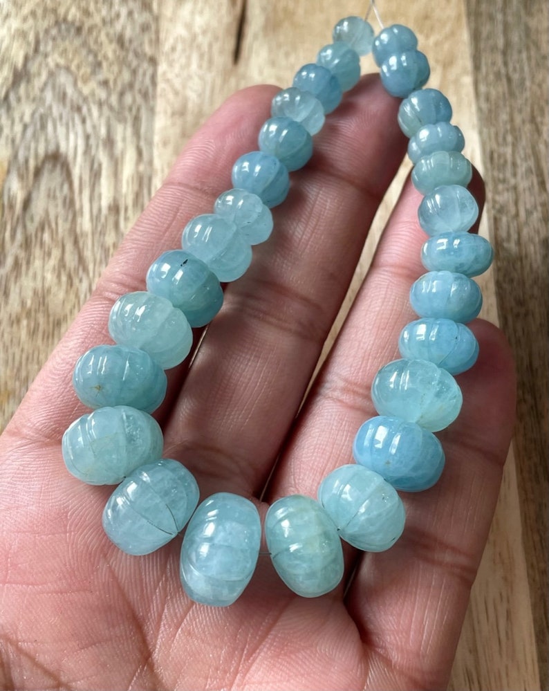 May include: A strand of light blue aquamarine beads, each bead is faceted and has a rounded, slightly elongated shape.