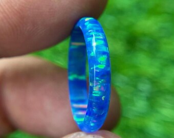以下が含まれることがあります： 虹色のオパールがあしらわれた薄い青いリング。リングは滑らかで磨かれた素材で作られており、シンプルでエレガントなデザインです。