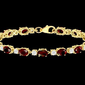 Puede incluir: Un brazalete de oro con una fila de piedras preciosas rojas ovaladas y piedras blancas redondas más pequeñas.
