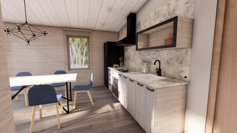 Puede incluir: Vista interior de una cocina moderna con gabinetes de madera clara y encimera de m&aacute;rmol. Se ven una campana extractora y un refrigerador negros. Una mesa de comedor con sillas azules est&aacute; en primer plano. Una ventana proporciona luz natural.