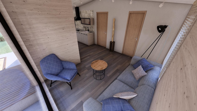 Puede incluir: Vista interior de un espacio de vida moderno con un sill&oacute;n azul, un sof&aacute; gris y una peque&ntilde;a mesa redonda de madera. La habitaci&oacute;n tiene pisos y paredes de madera, con dos puertas de madera y una cocina en el fondo.