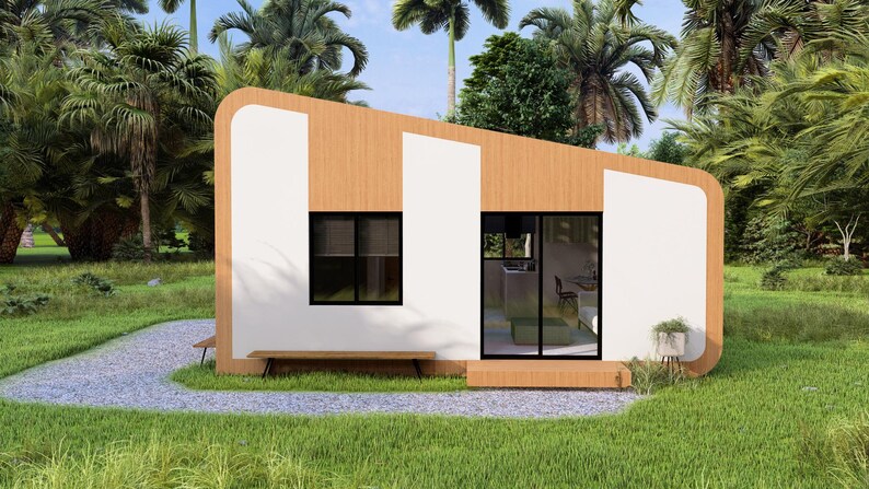 Puede incluir: Una peque&ntilde;a casa moderna de madera con detalles en blanco. La casa tiene un techo inclinado y grandes ventanas. Un peque&ntilde;o banco est&aacute; situado frente a la casa. La casa est&aacute; rodeada de exuberante hierba verde y palmeras.