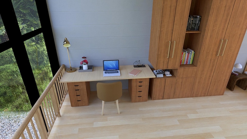 May include: A modern home office setup featuring a light wood desk with drawers, a laptop, and a tan chair. A built-in wooden cabinet provides storage. A gold desk lamp and a small floral arrangement add decorative touches. The room has a large window.