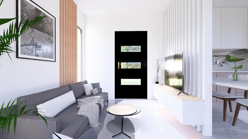 Op de afbeelding: Een moderne woonkamer met een grijze bank, een zwarte deur met rechthoekige ramen en een ronde salontafel. Een groot ingelijst kunstwerk hangt aan de muur. De kamer heeft witte muren en een lichtgekleurde vloer.
