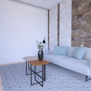 Peut inclure: Salon moderne avec un canap&eacute; blanc, des coussins bleu clair et un tapis &agrave; motifs. Deux petites tables en bois avec des pieds en m&eacute;tal noir sont devant le canap&eacute;. Un vase noir avec de la verdure et une lampe noire sont &eacute;galement pr&eacute;sents.
