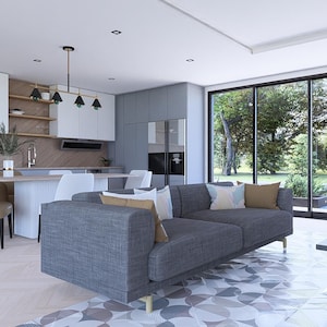 May include: Contemporary living room with a grey sofa, black coffee table, and a kitchen in the background. Large windows offer views of a green outdoor area. The decor is minimalist and modern, with a neutral colour palette.