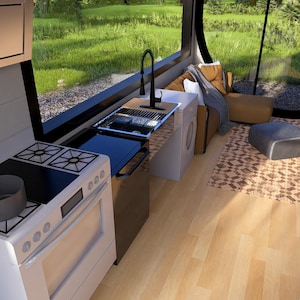 May include: Interior view of a tiny home kitchen with a white stove, a sink, and a black faucet. A gray pot sits on the stove. The kitchen has a large window with a view of green grass and trees. A small rug and seating area are visible.
