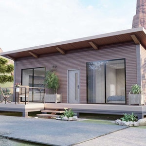 May include: A modern, single-story house with a brown exterior, large glass windows, and a wooden deck. The house has a flat roof with exposed wooden beams and is surrounded by trees and a paved driveway. The landscape includes a mountain backdrop.