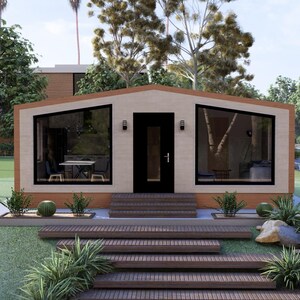 Puede incluir: Una casa moderna de una sola planta con fachada beige, ventanas con marcos negros y una puerta oscura. La casa tiene un tejado inclinado y est&aacute; rodeada de vegetaci&oacute;n, incluyendo hierba, &aacute;rboles y arbustos. Unas escaleras de madera conducen a la entrada.