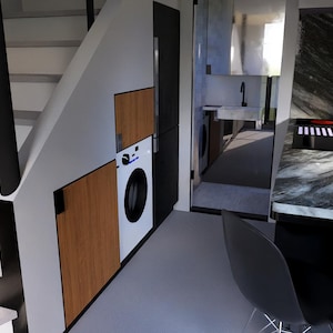 以下が含まれることがあります： モダンでミニマリストな家の内観。階段、洗濯機、大理石のカウンタートップを備えたキッチンエリアがあります。デザインは木と黒のアクセントを取り入れています。