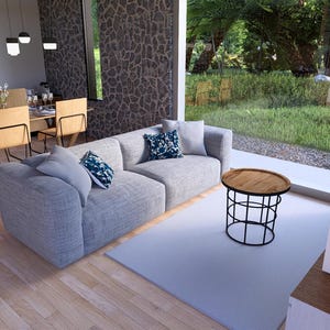 May include: Modern living room with a light gray sectional sofa, decorative pillows, and a round wooden coffee table with a black metal base. A dining area with a wooden table and chairs is visible.