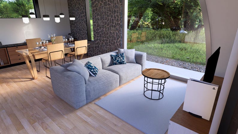 May include: Modern living room with a light gray sectional sofa, decorative pillows, and a round wooden coffee table with a black metal base. A dining area with a wooden table and chairs is visible.