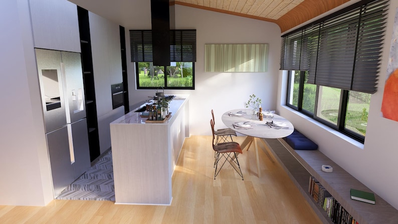 Puede incluir: Interior de cocina moderno con una isla blanca, nevera de acero inoxidable y zona de comedor con mesa redonda y sillas. La habitaci&oacute;n cuenta con grandes ventanales con persianas y suelo de madera.