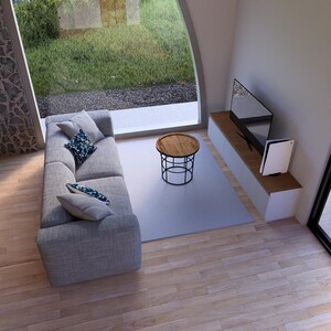 May include: An interior shot of a modern living room with a gray sofa, a round coffee table, and a wall-mounted TV. The room has large windows overlooking a green outdoor area. A dining table with chairs is also visible.