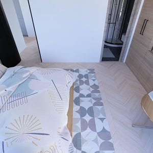May include: Bedroom interior featuring a bed with a patterned duvet cover and pillows. A geometric rug in grey and white tones is at the foot of the bed. Light wood flooring and a wooden cabinet are also visible.