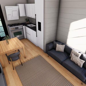 Puede incluir: Vista interior de un espacio habitable peque&ntilde;o y moderno. Incluye una cocina con armarios blancos, un comedor con mesa y silla de madera, y un sof&aacute; azul con cojines. La habitaci&oacute;n tiene suelos de madera y una alfombra a rayas.