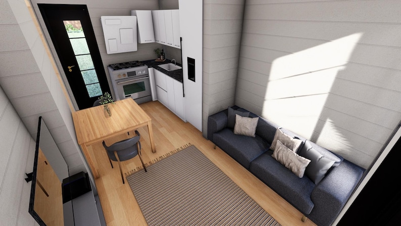 Puede incluir: Vista interior de un espacio habitable peque&ntilde;o y moderno. Incluye una cocina con armarios blancos, un comedor con mesa y silla de madera, y un sof&aacute; azul con cojines. La habitaci&oacute;n tiene suelos de madera y una alfombra a rayas.