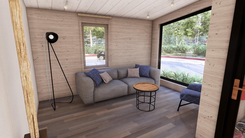 Puede incluir: Un sal&oacute;n moderno con un sof&aacute; gris, cojines azules y beige, y una mesa de centro redonda de madera. Una l&aacute;mpara de pie negra y un sill&oacute;n azul tambi&eacute;n est&aacute;n presentes. Grandes ventanales ofrecen vistas al exterior.