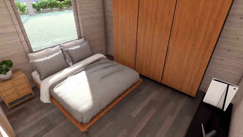 Puede incluir: Interior de dormitorio con cama, almohadas y armario de madera. La cama tiene una colcha gris y almohadas. Una peque&ntilde;a mesita de noche de madera con cajones est&aacute; al lado de la cama. Una ventana ofrece vistas al exterior.