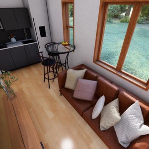 May include: Interior shot of a modern tiny home. Features include a brown leather sofa with decorative pillows, a small kitchen with dark gray cabinets, and a dining area with a round table and stools. Large windows offer a view of the outdoors.