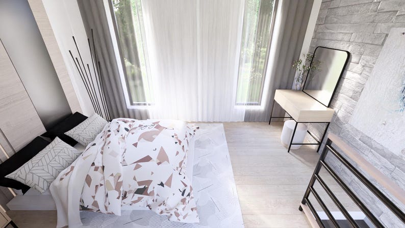 Op de afbeelding: Een moderne slaapkamer met een bed bedekt met een patroon dekbed en kussens. De kamer heeft een kaptafel met een zwart omlijste spiegel, een groot raam met transparante gordijnen en een lichte houten vloer. De muren zijn een mix van licht hout en steen.
