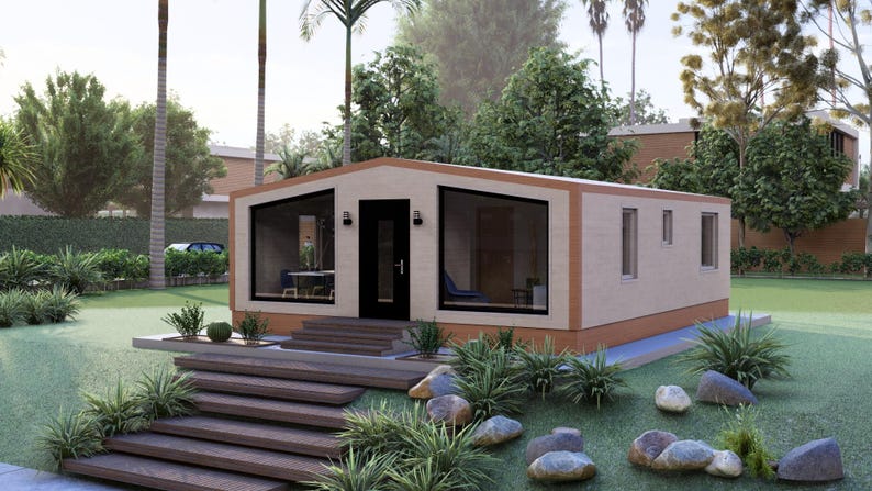 Puede incluir: Una casa prefabricada moderna con exterior beige, grandes ventanas y una puerta oscura. La casa est&aacute; rodeada de un jard&iacute;n paisaj&iacute;stico con escaleras, plantas y rocas. El dise&ntilde;o es contempor&aacute;neo y minimalista.