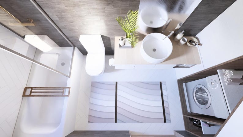 Op de afbeelding: Een bovenaanzicht van een moderne badkamer met witte armaturen en een neutraal kleurenpalet. De kamer omvat een toilet, een douche, een dubbele wastafel en een wasmachine. Een decoratief tapijt met een golfpatroon.