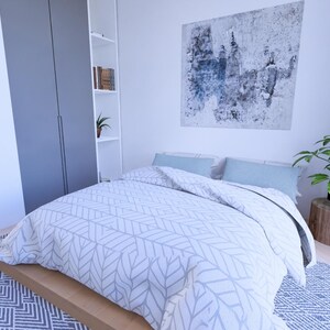 Peut inclure: Chambre moderne avec lit dot&eacute; d'une couette &agrave; motifs blancs et gris et de coussins bleu clair. Une grande peinture abstraite est accroch&eacute;e au-dessus du lit. Une plante en pot repose sur une souche de bois et un tapis &agrave; motifs est au sol.