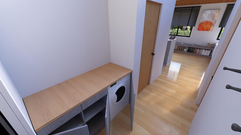 Puede incluir: Un lavadero con una encimera de madera clara y un armario gris con estantes abiertos. Una lavadora blanca est&aacute; integrada en el armario. La habitaci&oacute;n tiene suelo de madera clara y una puerta marr&oacute;n claro.