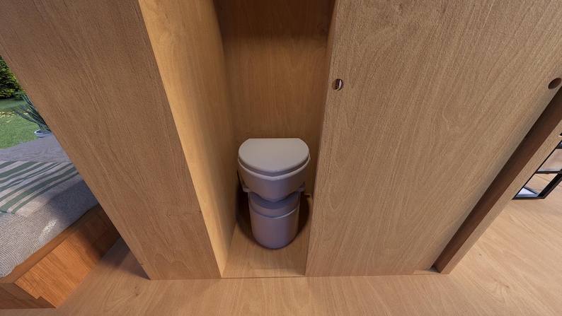 Pu&ograve; includere: Un WC a compostaggio grigio chiaro &egrave; inserito in un involucro di legno. Il WC ha un sedile arrotondato e una base cilindrica. Le pareti e la porta circostanti sono in legno chiaro, creando un'estetica minimalista.