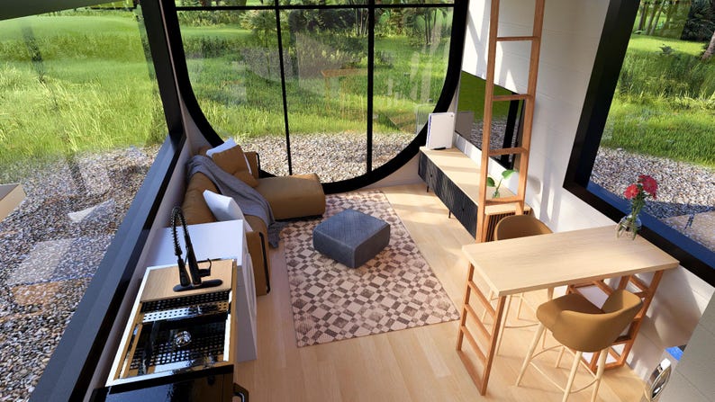 May include: Interior view of a modern living space with large windows overlooking a green landscape. The room features a sofa, coffee table, dining table, and a built-in entertainment center. The decor includes a patterned rug and wooden accents.