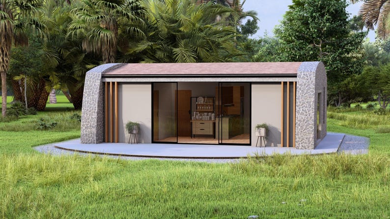 May include: A modern, single-story home with a stone facade and a flat roof. The home has large sliding glass doors and is surrounded by lush greenery. The interior features a kitchen and living area.