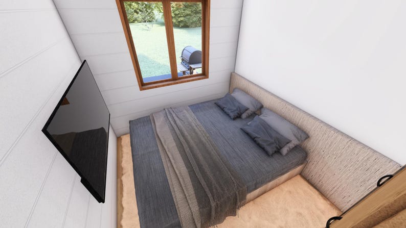 May include: A bedroom with a bed, pillows, and a blanket. A large black television is mounted on the wall. A window with a view of the outdoors is visible.