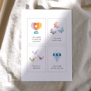 May include: Four colorful affirmation cards with illustrations. The first card features a hot air balloon with a heart and the text "I am capable of achieving my dreams". The second card features butterflies and the text "I can make friends easily". The third card features birds and the text "My voice is important". The fourth card features a diamond and the text "I am enough just the way I am".