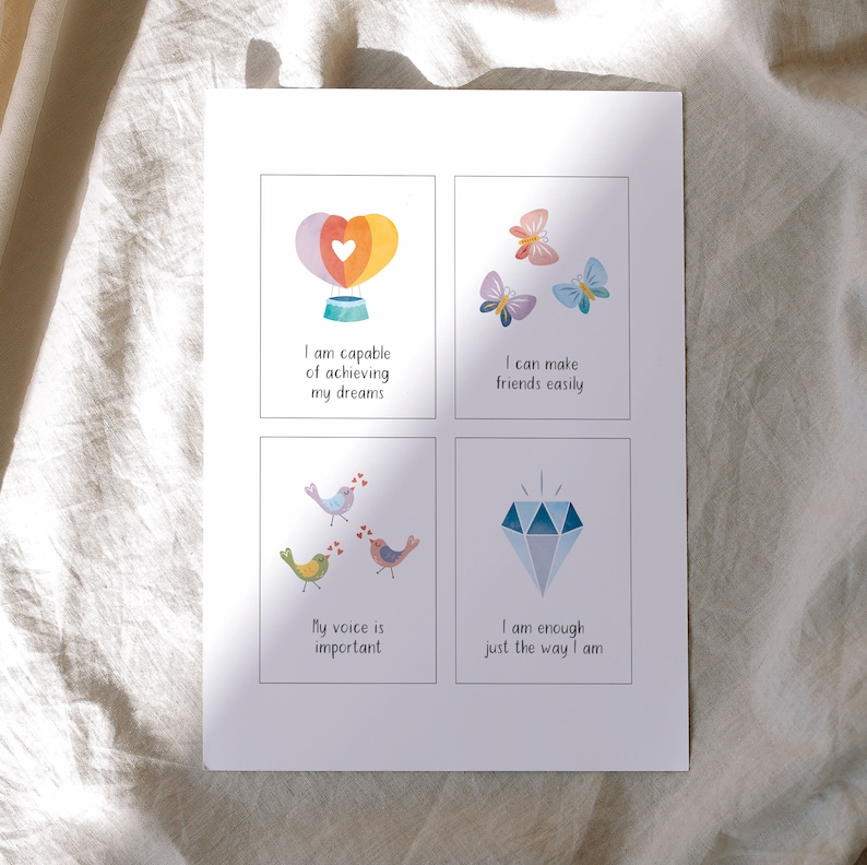May include: Four colorful affirmation cards with illustrations. The first card features a hot air balloon with a heart and the text "I am capable of achieving my dreams". The second card features butterflies and the text "I can make friends easily". The third card features birds and the text "My voice is important". The fourth card features a diamond and the text "I am enough just the way I am".