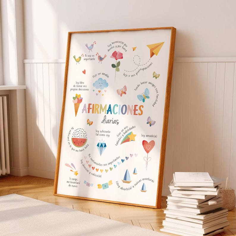 May include: A framed print with the words "AFIRMACIONES diarias" in colorful letters. The print features various illustrations, including birds, flowers, butterflies, and a watermelon slice. The frame is a warm brown color, and the print is leaning against a wall.