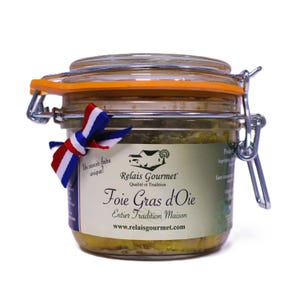 Può includere: Un barattolo di vetro di foie gras con chiusura in metallo e guarnizione in gomma arancione. Il barattolo ha un'etichetta con testo francese e un nastro tricolore. Il barattolo è pieno di paté chiaro.
