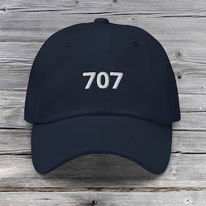 Könnte beinhalten: Eine marineblaue Baseballkappe mit der Nummer 707 in weiß auf der Vorderseite gestickt.