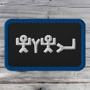 May include: A black embroidered patch with a blue border. The patch features a white stylized design of three stick figures with raised arms and a white arrow pointing to the right.