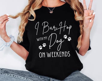 May include: Black t-shirt with white text that reads "I Bar-Hop With My Dog On Weekends" and paw prints.
