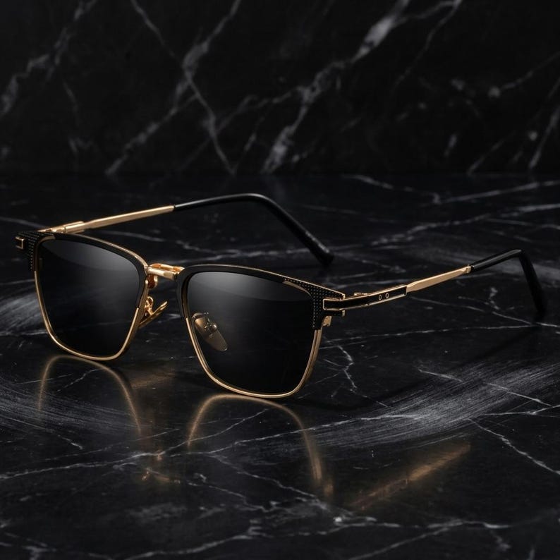 Puede incluir: Gafas de sol de montura cuadrada con montura de metal dorado y negro. Las gafas de sol tienen lentes oscuras y un dise&ntilde;o elegante y moderno. Las patillas son doradas y la montura tiene un detalle texturizado cerca de las bisagras.