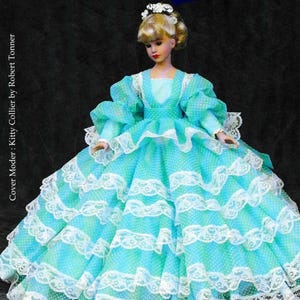 May include: A doll wearing a turquoise and white polka-dot dress with multiple ruffled layers and white lace trim. The doll has blonde hair and a floral headpiece. The text "Virginia" and "A Pattern to Fit 10" Coquette Cissy" are visible.