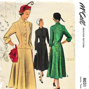 May include: A vintage sewing pattern for a two-piece suit for a junior doll. The pattern is from McCall's and is number 8031. The suit is shown in two different colors: a beige suit and a green suit with white polka dots. The doll is wearing a red hat and white gloves.