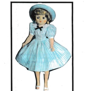 Puede incluir: Una muñeca vintage que lleva un vestido a rayas azules y blancas con un cuello blanco y un lazo negro. La muñeca lleva un sombrero azul y zapatos blancos.