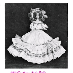 May include: A black and white photo of a doll wearing a white dress with lace trim and a large, ruffled skirt. The doll is wearing a white veil and has a pearl necklace. The doll is standing on a black background. The text "250 Southern Lady Belle" is printed below the doll.