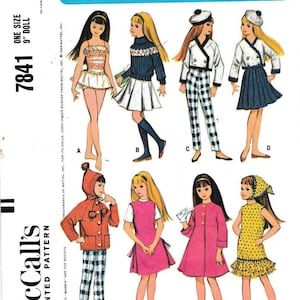 May include: A McCall's printed pattern envelope for a 9-inch Skipper doll, featuring illustrations of eight different outfits labeled A through H. The blue header displays the text Official Barbie's Little Sister Skipper Doll's Instant Fabric Wardrobe.