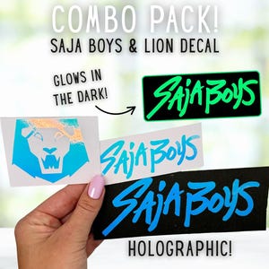 Könnte beinhalten: Ein Kombipack aus Aufklebern mit dem Text "SAJA BOYS" in Neongrün und Blau sowie einem holografischen Löwen-Design. Ein Aufkleber leuchtet im Dunkeln. Das Wort "HOLOGRAPHIC!" ist ebenfalls sichtbar.
