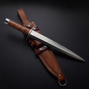 May include: A long, silver dagger with a brown leather handle and a matching leather sheath. The dagger has a pointed tip and a straight blade.