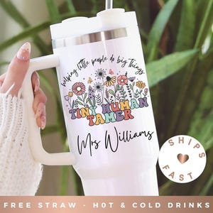 May include: White tumbler with a handle, featuring the text "helping little people do big things" and "TINY HUMAN TAMER" in colorful lettering. The design includes floral elements and the name "Mrs Williams". The tumbler is designed for hot and cold drinks.